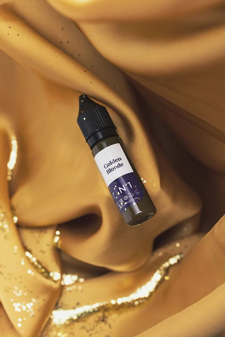 Hanafy Golden Blonde eyebrow pigment bottle on luxurious gold fabric with glitter detailing.